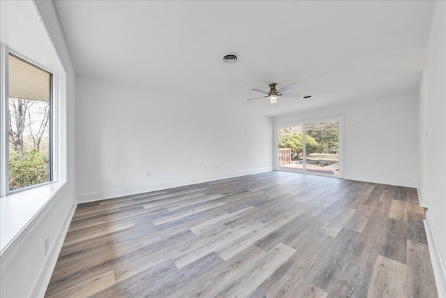 unfurnished room with ceiling fan, visible vents, baseboards, and wood finished floors