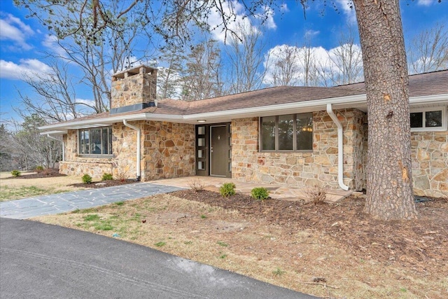 single story home featuring stone siding and a chimney