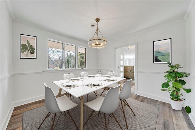 dining space featuring ornamental molding, baseboards, an inviting chandelier, and wood finished floors