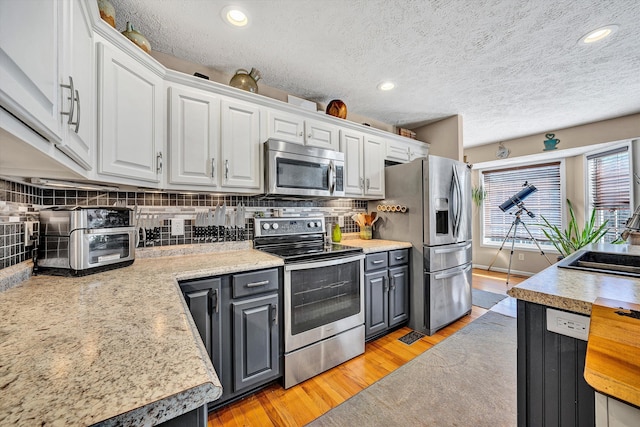 kitchen with white cabinets, light wood-type flooring, appliances with stainless steel finishes, and light countertops