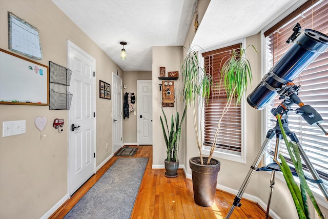 entryway featuring a textured ceiling, baseboards, and wood finished floors