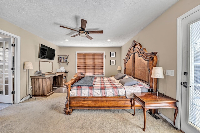 bedroom with ceiling fan, multiple windows, a textured ceiling, and light colored carpet