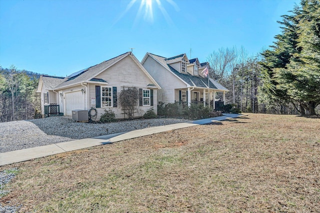 view of front facade with a porch, central air condition unit, a garage, driveway, and a front yard