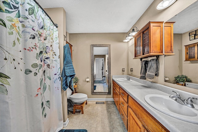 bathroom with a textured ceiling, a sink, toilet, and baseboards