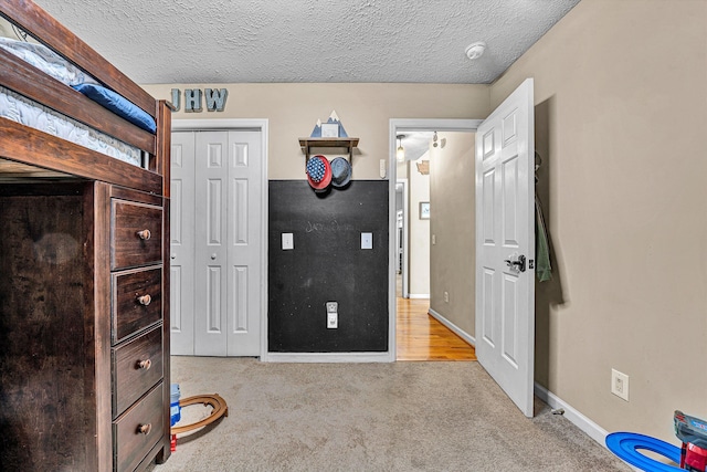 unfurnished bedroom with a textured ceiling, a closet, carpet, and baseboards