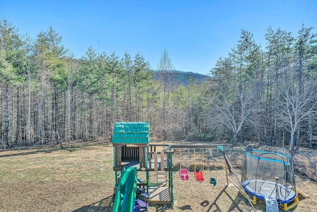 view of yard with a playground and a wooded view