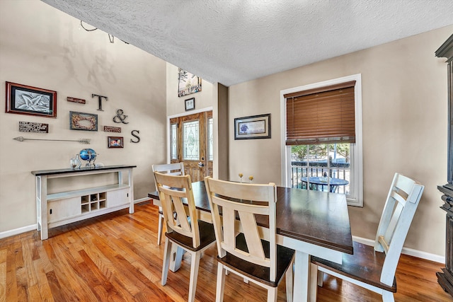 dining area featuring a textured ceiling, baseboards, and wood finished floors