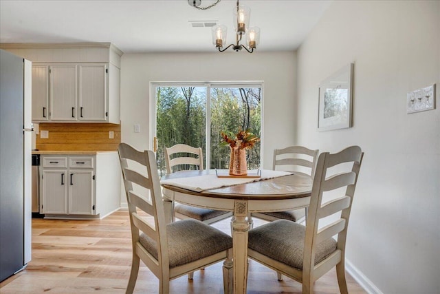 dining area with a chandelier, visible vents, baseboards, and light wood-style floors