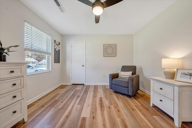 sitting room with visible vents, light wood-style flooring, baseboards, and a ceiling fan