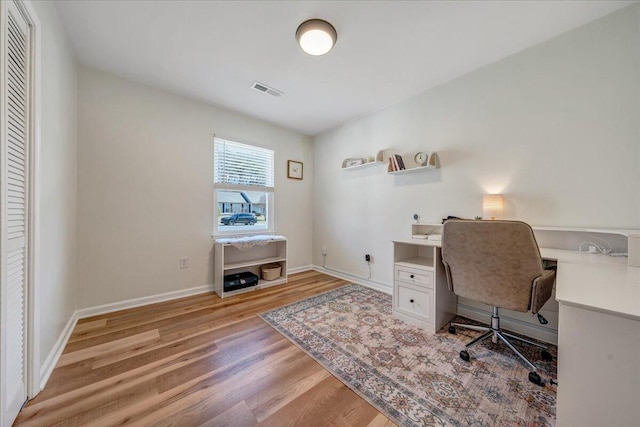 home office featuring visible vents, light wood-style flooring, and baseboards