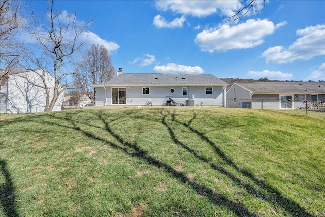 back of property with a yard, fence, and central AC