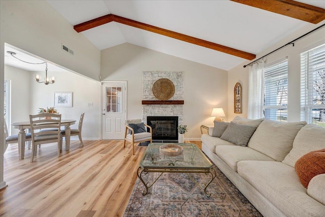 living area with visible vents, vaulted ceiling with beams, a fireplace, light wood-type flooring, and a chandelier