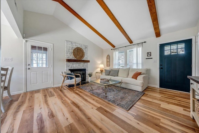 living area with beamed ceiling, high vaulted ceiling, light wood-style floors, a fireplace, and baseboards