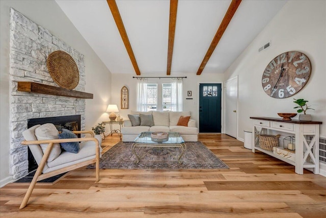 living room with beamed ceiling, visible vents, high vaulted ceiling, wood finished floors, and a fireplace