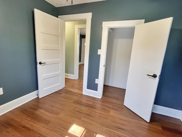 unfurnished bedroom with baseboards and wood finished floors