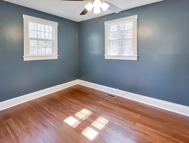 spare room featuring plenty of natural light, baseboards, and visible vents