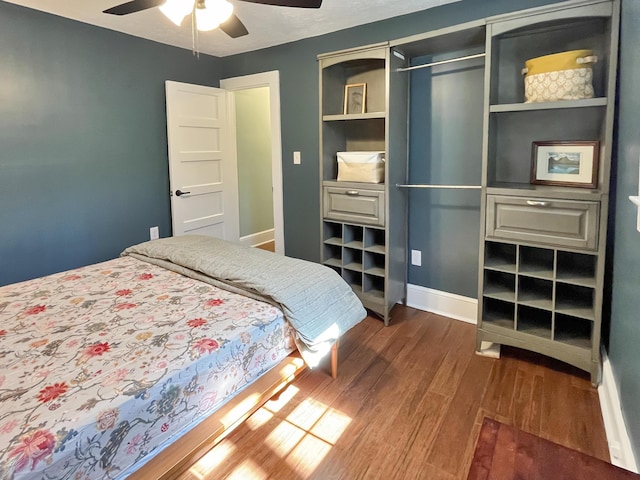 bedroom featuring a closet, ceiling fan, baseboards, and dark wood-style flooring