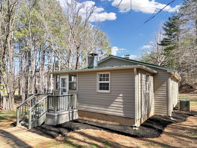 rear view of property with cooling unit and a chimney