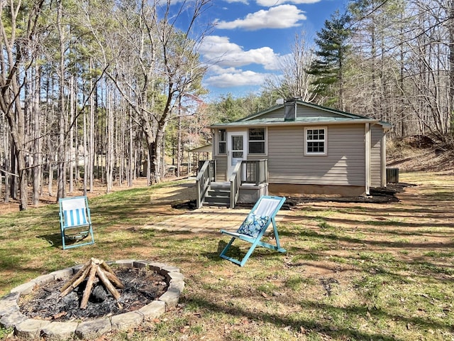 back of house with a yard and a fire pit