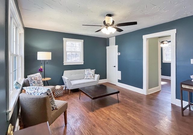 living area with baseboards, a textured ceiling, wood finished floors, and a ceiling fan