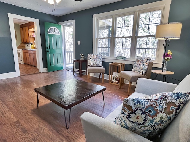 living room featuring baseboards, a baseboard heating unit, a ceiling fan, and wood finished floors