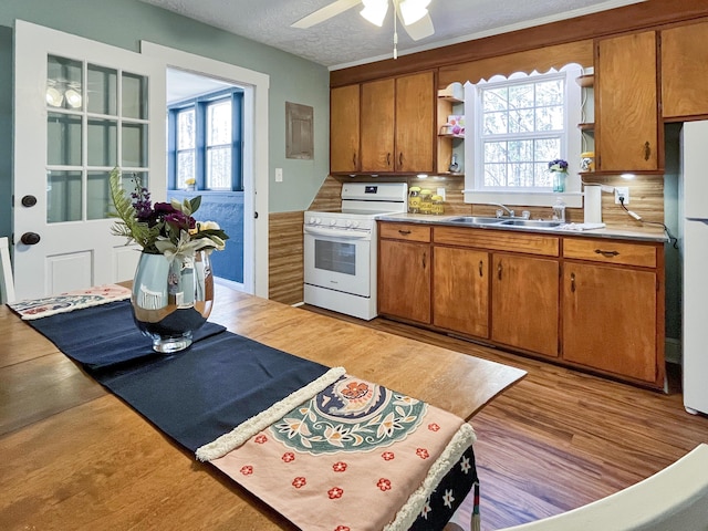 kitchen with open shelves, brown cabinets, white appliances, and a sink