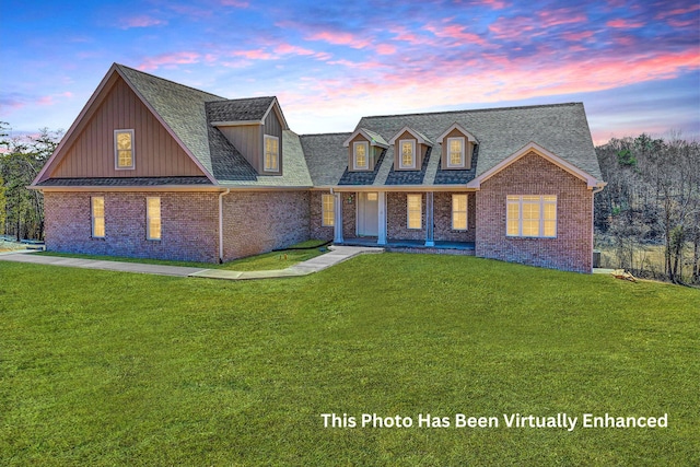 view of front of house featuring brick siding, a lawn, and a shingled roof