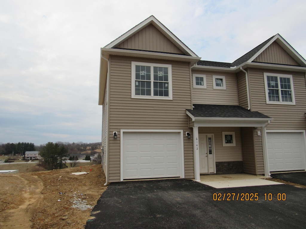 view of property featuring aphalt driveway, board and batten siding, and an attached garage