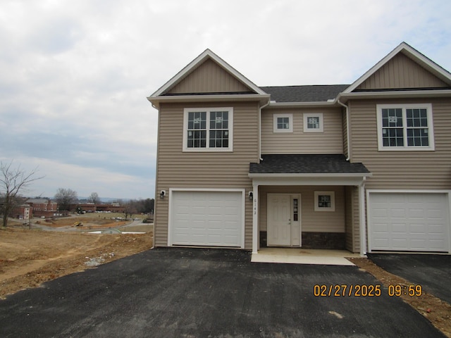 view of front facade featuring driveway, a shingled roof, and a garage