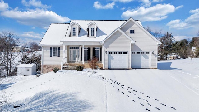 cape cod home with a storage shed, covered porch, an attached garage, and an outbuilding