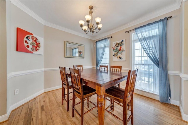 dining area featuring ornamental molding, light wood finished floors, a notable chandelier, and baseboards