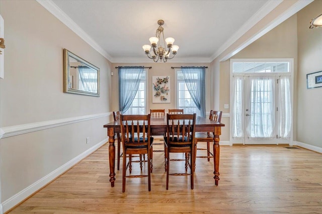 dining room featuring light wood-type flooring, crown molding, baseboards, and a notable chandelier