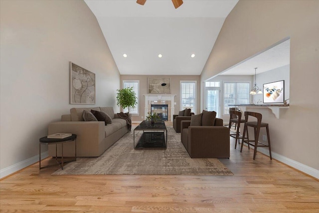 living room with baseboards, high vaulted ceiling, and wood finished floors