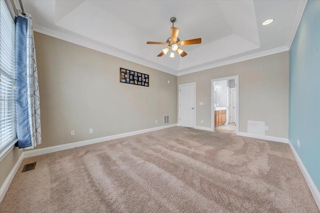 unfurnished bedroom with a tray ceiling, carpet, visible vents, and baseboards