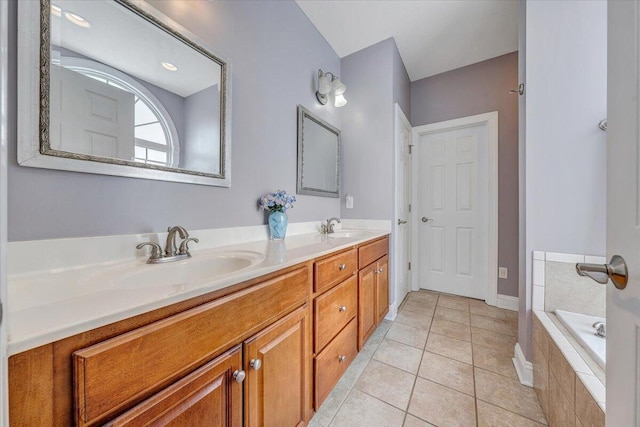 bathroom with double vanity, tiled tub, a sink, and tile patterned floors