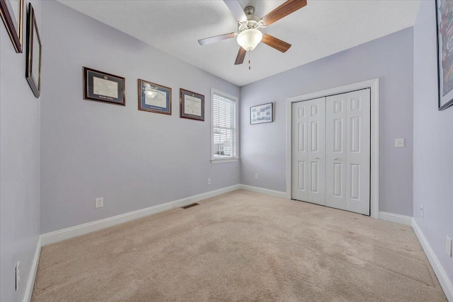 unfurnished bedroom featuring a closet, visible vents, a ceiling fan, light carpet, and baseboards