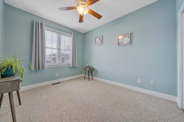 carpeted spare room with a ceiling fan, visible vents, and baseboards