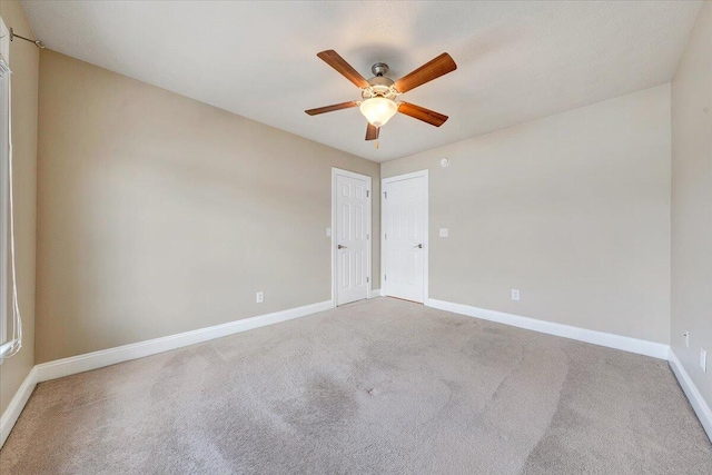 empty room featuring light colored carpet, ceiling fan, and baseboards