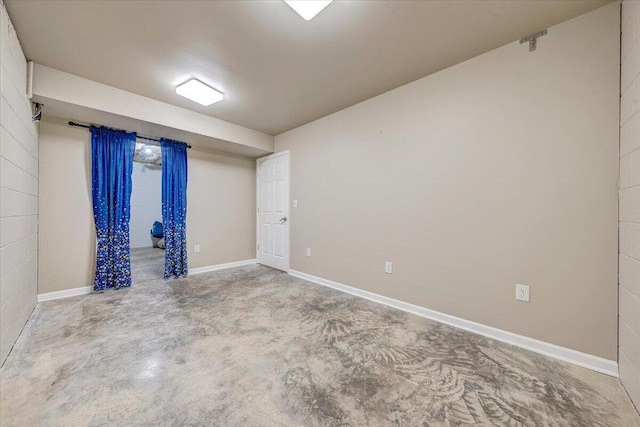 spare room featuring concrete flooring and baseboards