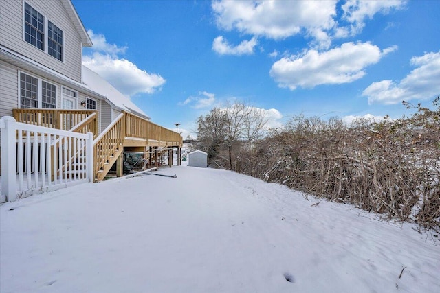 yard covered in snow featuring a wooden deck and stairs