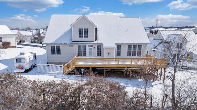 snow covered back of property featuring fence and a deck