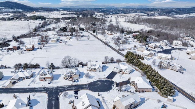 snowy aerial view featuring a mountain view and a residential view