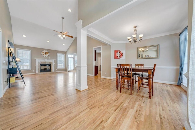 dining area featuring a high end fireplace, light wood-type flooring, baseboards, and ceiling fan with notable chandelier