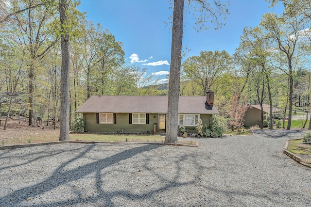 ranch-style house with gravel driveway and a chimney
