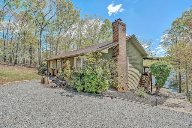 view of property exterior with a chimney and stairway
