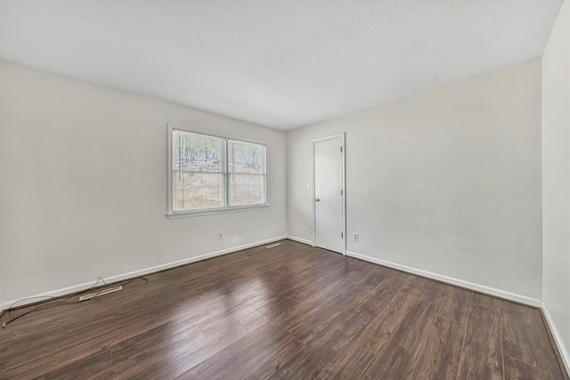 empty room with baseboards, dark wood-type flooring, and a textured ceiling