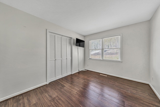 unfurnished bedroom with visible vents, baseboards, wood finished floors, and a closet