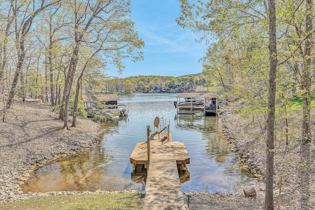 dock area featuring a wooded view and a water view