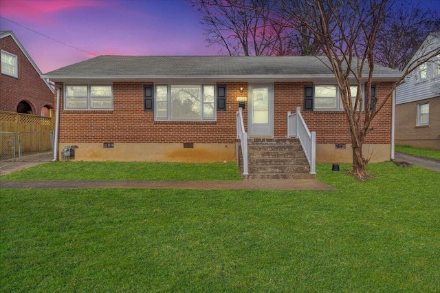 view of front of property featuring brick siding, a shingled roof, fence, a yard, and crawl space