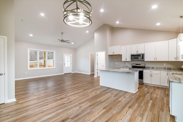 kitchen with open floor plan, a kitchen island, high vaulted ceiling, and stainless steel appliances